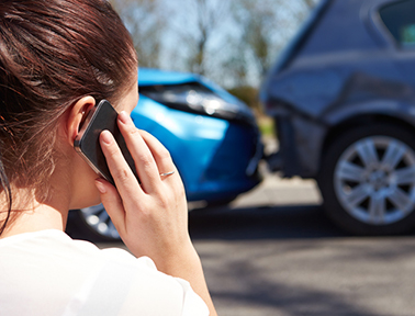 Woan on phone in front of a car accident. 
