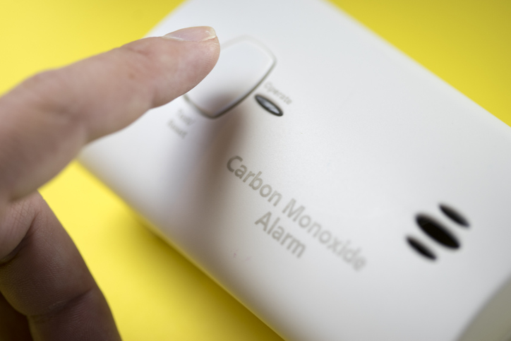 A finger pushing the button on a CO2 home detector.