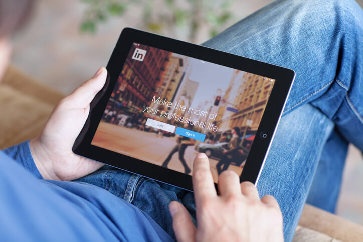 Man looking at the Linkedin page on a tablet.