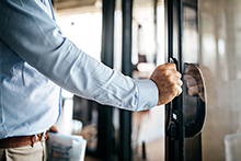 Businessman opening door entering office.