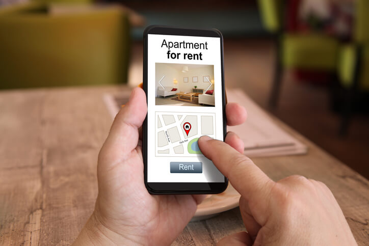 A man looking on his smartphone for apartments available rent.