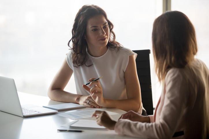 Two women meeting with their notes and computers.