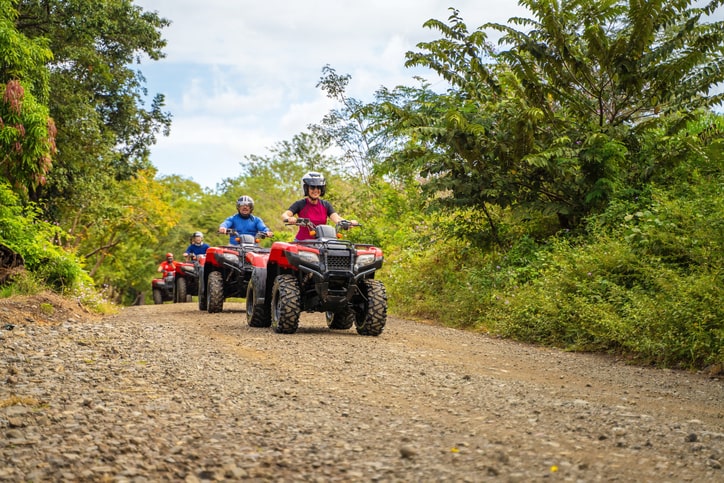 Group of people riding their ATVs down a trail path.