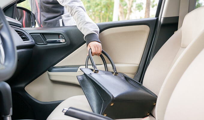 A thief stealing a purse from inside a car.