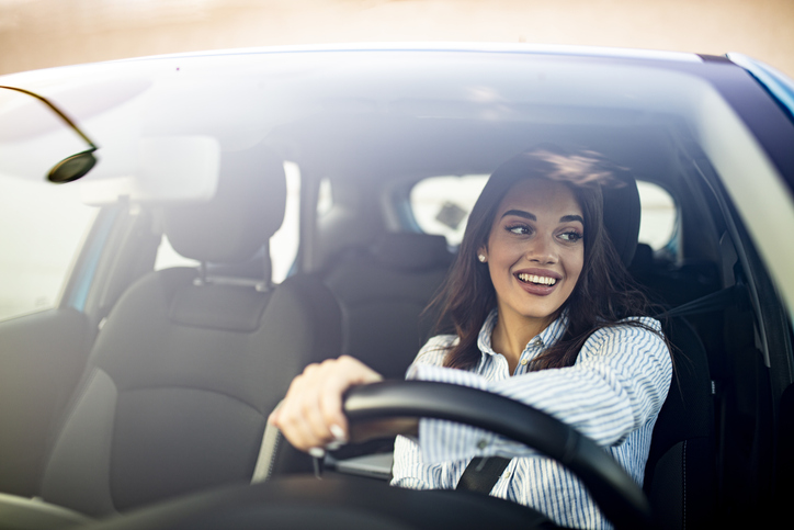 Woman driving while she is looking off to the left side of the road.