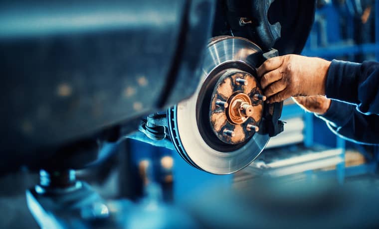 A mechanic installing at a brake pad on a car.