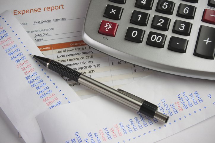 Pen and calculator on top receipts for a expense report.