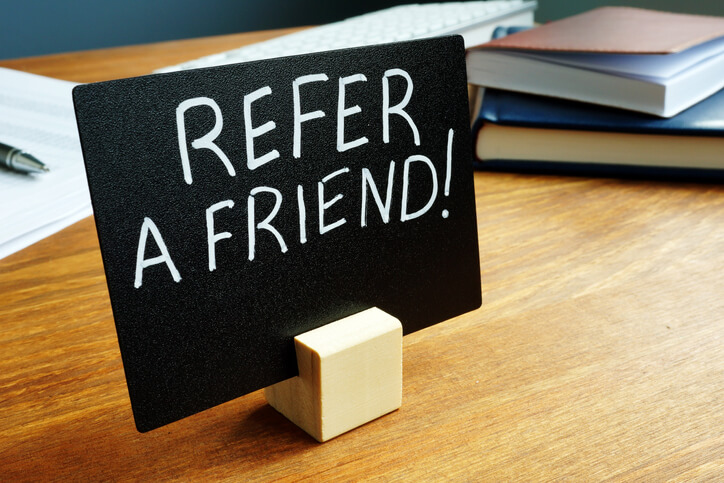 Desk note with a message stating Refer a Friend.