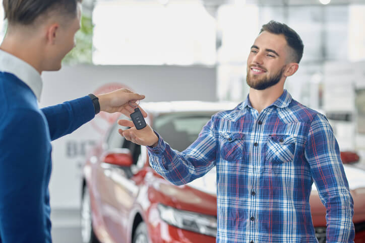 Salesman giving car keys to a male customer.