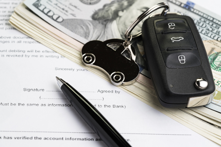 Car key fob on top money and car title paperwork.