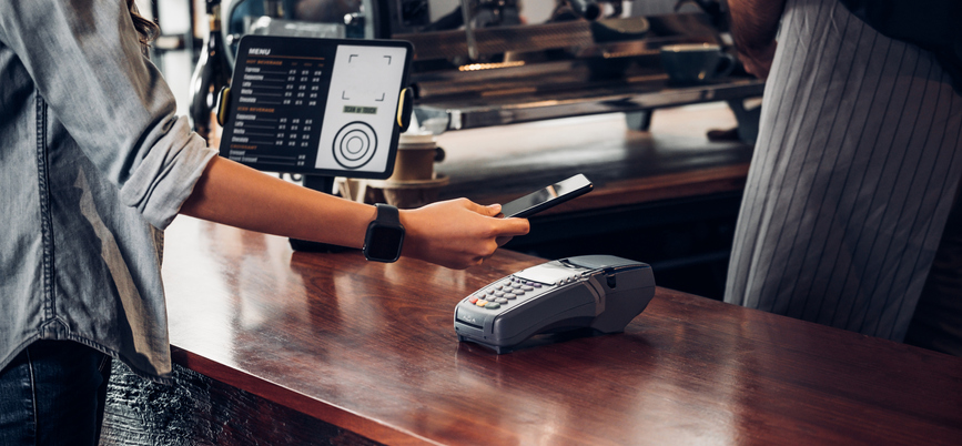 A person using their smartphone to pay at a cafe.