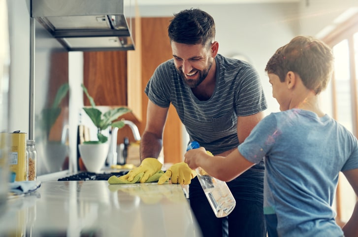 Father and son having fun cleaning the kitchen counter.