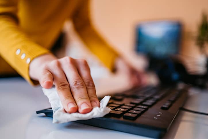 Person wiping down their computer keyboard.