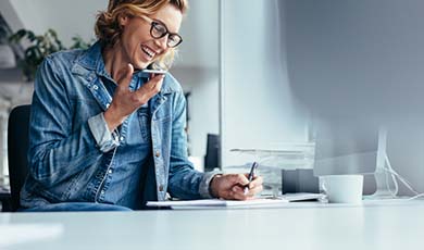 Woman talking on her phone while taking notes.
