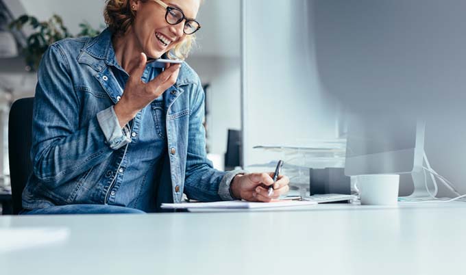Woman talking on her phone while taking notes.