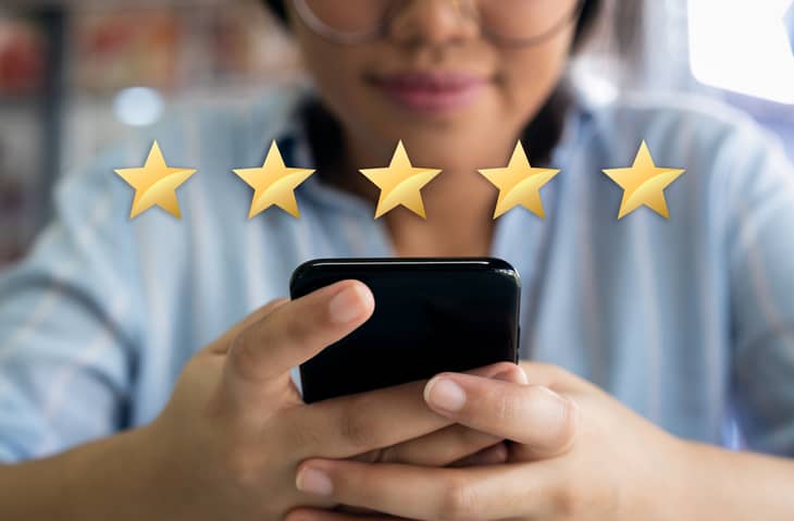 Woman on her smartphone with 5-stars displayed above the phone.