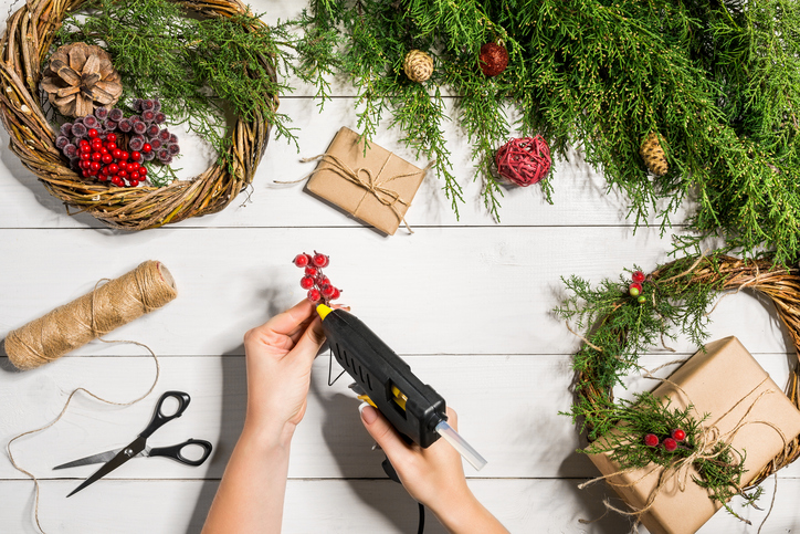 Person crafting fall decorations with a glue gun in their hand.