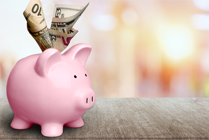 A piggy bank with cash stuffed in the top.