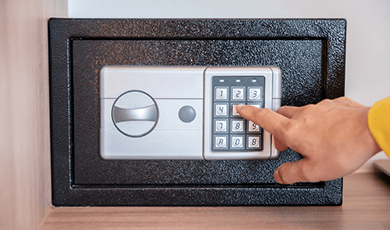 Person's finger touching the number keypad on safe lockbox.