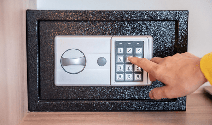 Person's finger touching the number keypad on safe lockbox.