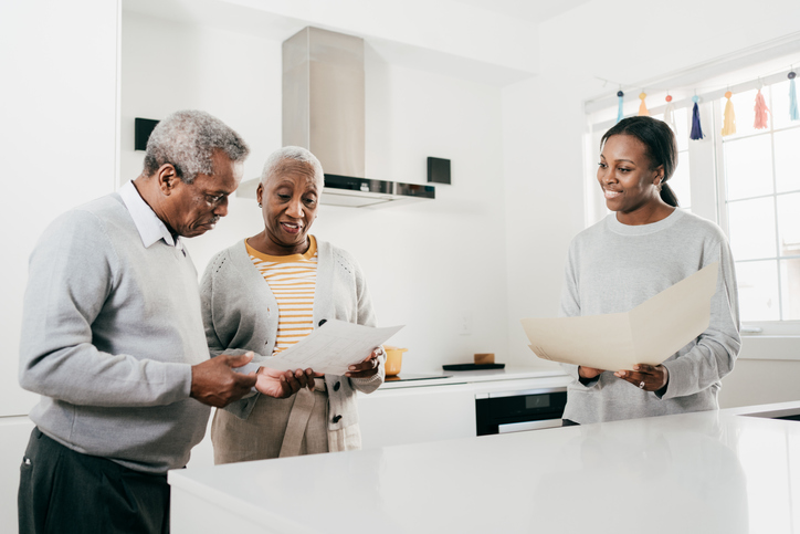 Elderly couple in their kitchen looking over paperwork with an agent.