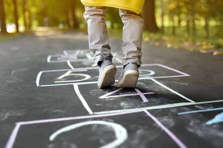 Kid's shoes on a hopscotch drawn board.