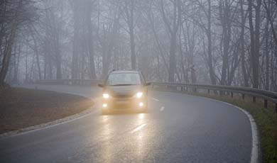 A car driving on a foggy road.