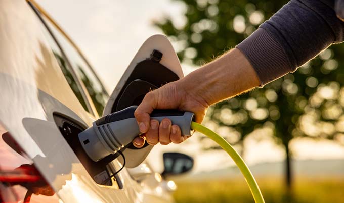 Male's hand plugging in a EV charger into his electric car.