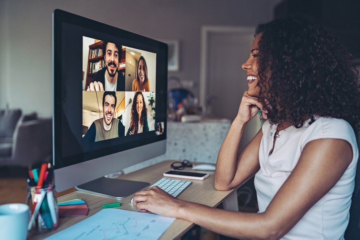 A woman smiling with her co-workers during a video conference call. 