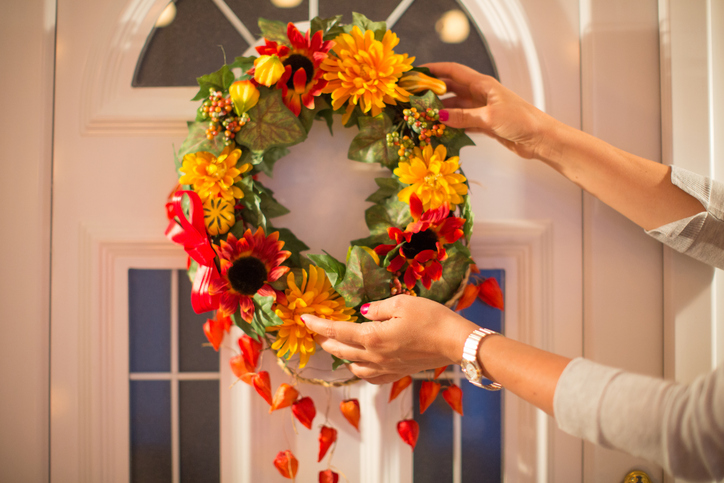 A woman holding up a fall reef on a door. 