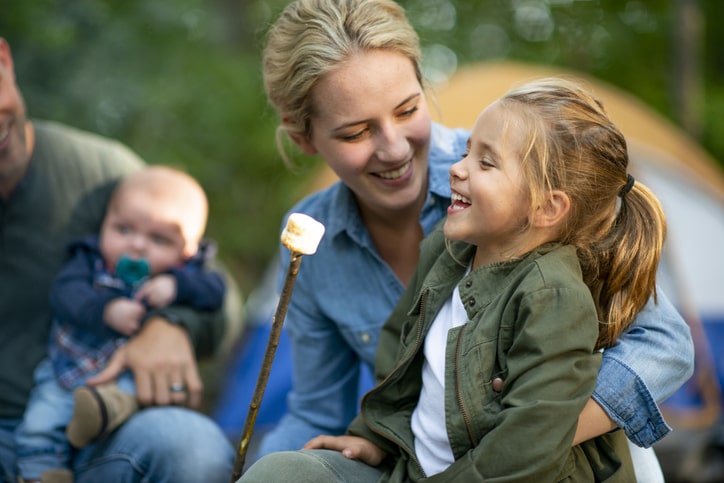 Family enjoying toasted marshmellows on camping grounds.
