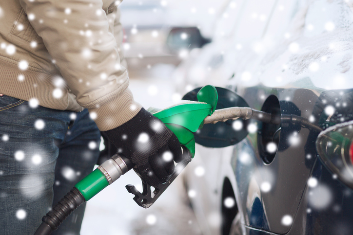 A driver using a gas pump to add fuel to their vehicle.