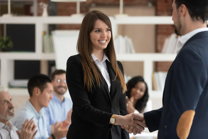 Woman shaking hands with her boss in meeting.