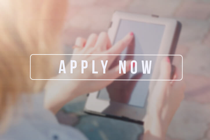 Apply now text-overlaying a woman using a ipad.