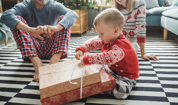 A boy opening up christmas gifts with parents.