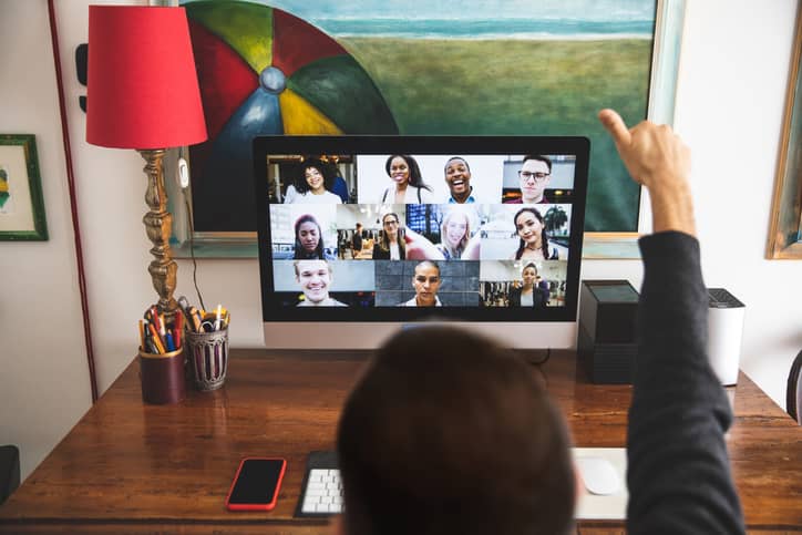 Man signaling a thumbs up in front of video conference group.