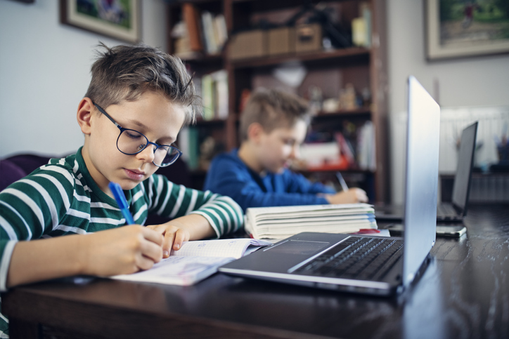 Two young boys learning on laptops.