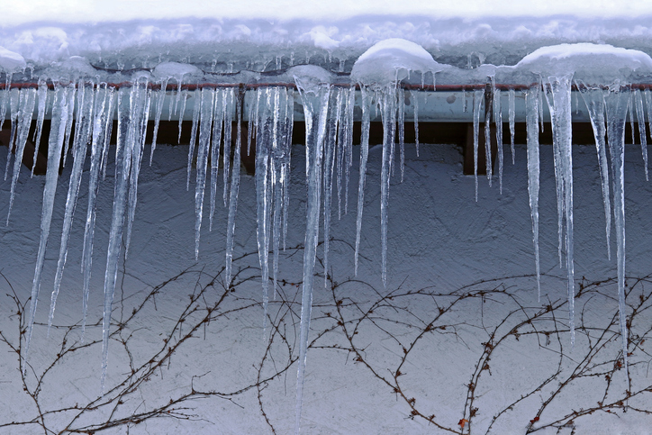 Long ice shards hanging from the side of a roof.