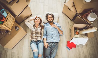 A couple laying on the floor among moving boxes. 
