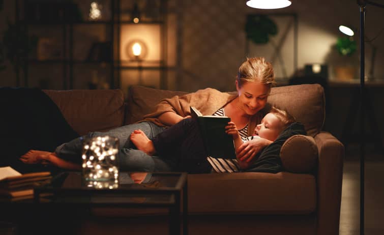 Mother on the couch reading to her son. 