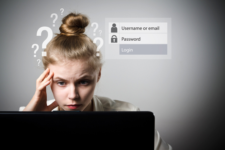 Woman sitting in front of her computer thinking of a password and username.