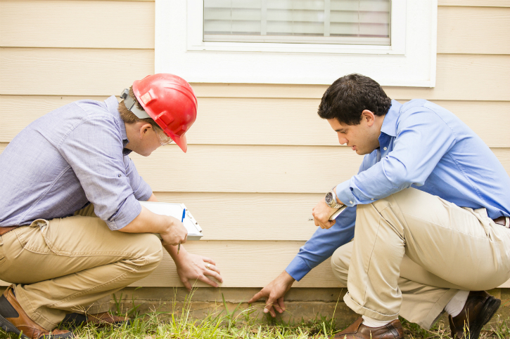 Exterminator examining a house with the homeowner.