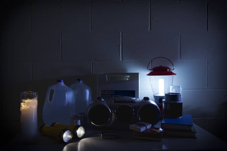 Light from a candle, two flashlights, and an electric lantern surround emergency supplies.