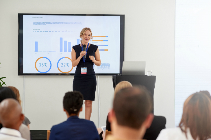 A woman presenting in front of the crowd.
