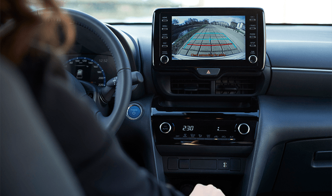 A woman looking at the rearview camera screen in the car.