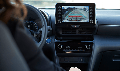 A woman looking at the rearview camera screen in the car.