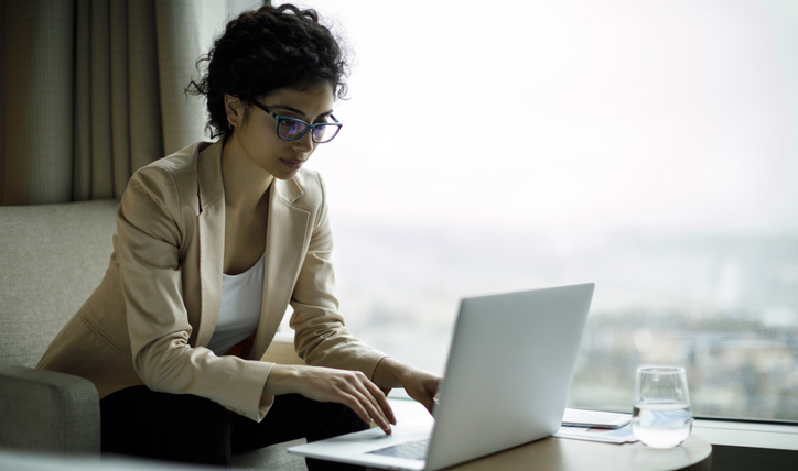 A woman using her laptop in a hotel room.