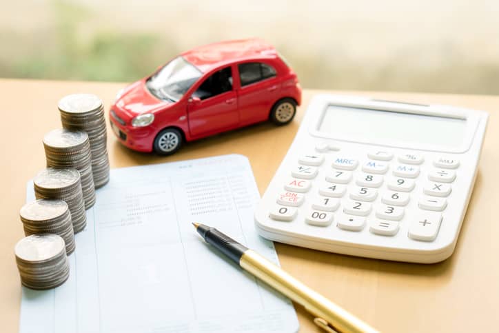 A stack of quarters on top of a budget paper next to a toy car and calculator.