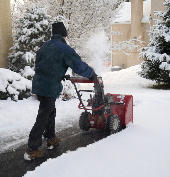 Man operating his snowblower on a sidewalk.