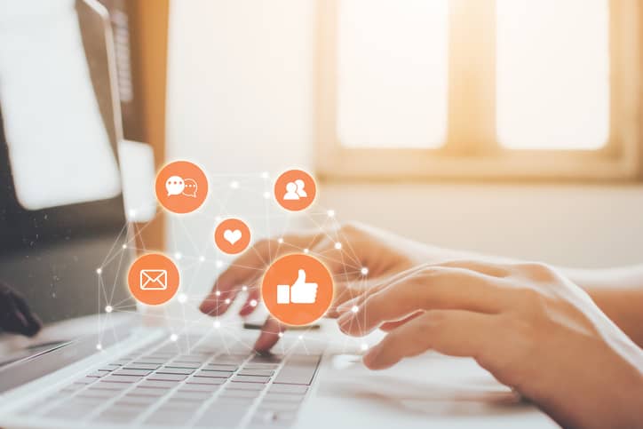 Social media icons floating above a personâ€™s keyboard.
